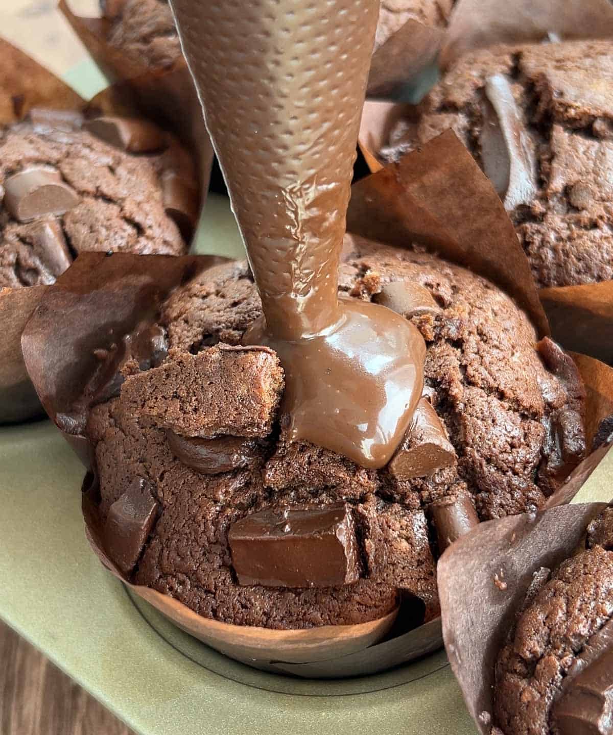 chocolate ganache being piped into the chocolate muffin.