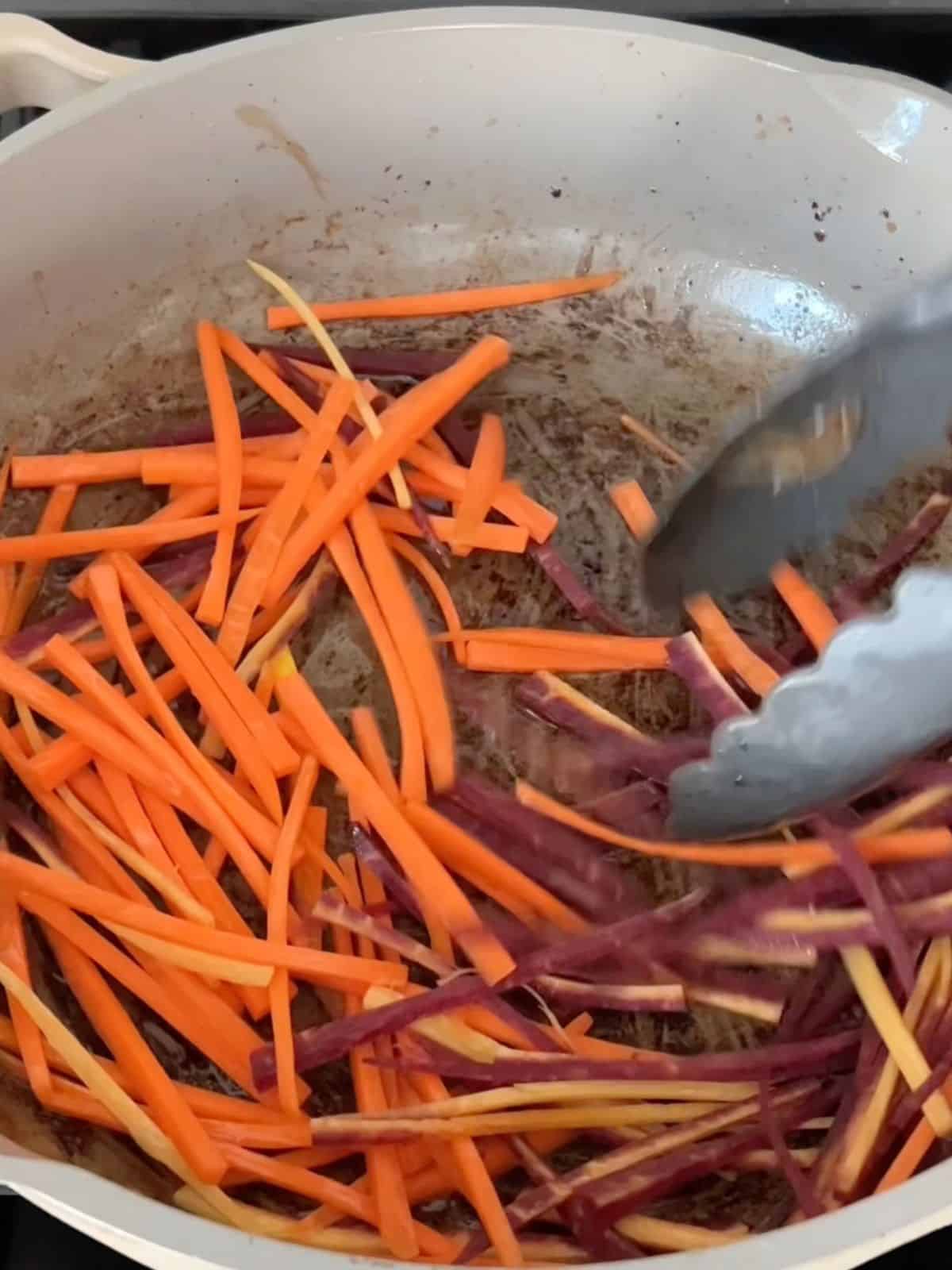 Carrots being cooked in a skillet on the stove. 