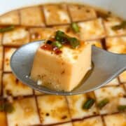 Cube of steamed egg white on a spoon with more steamed egg whites in the background.