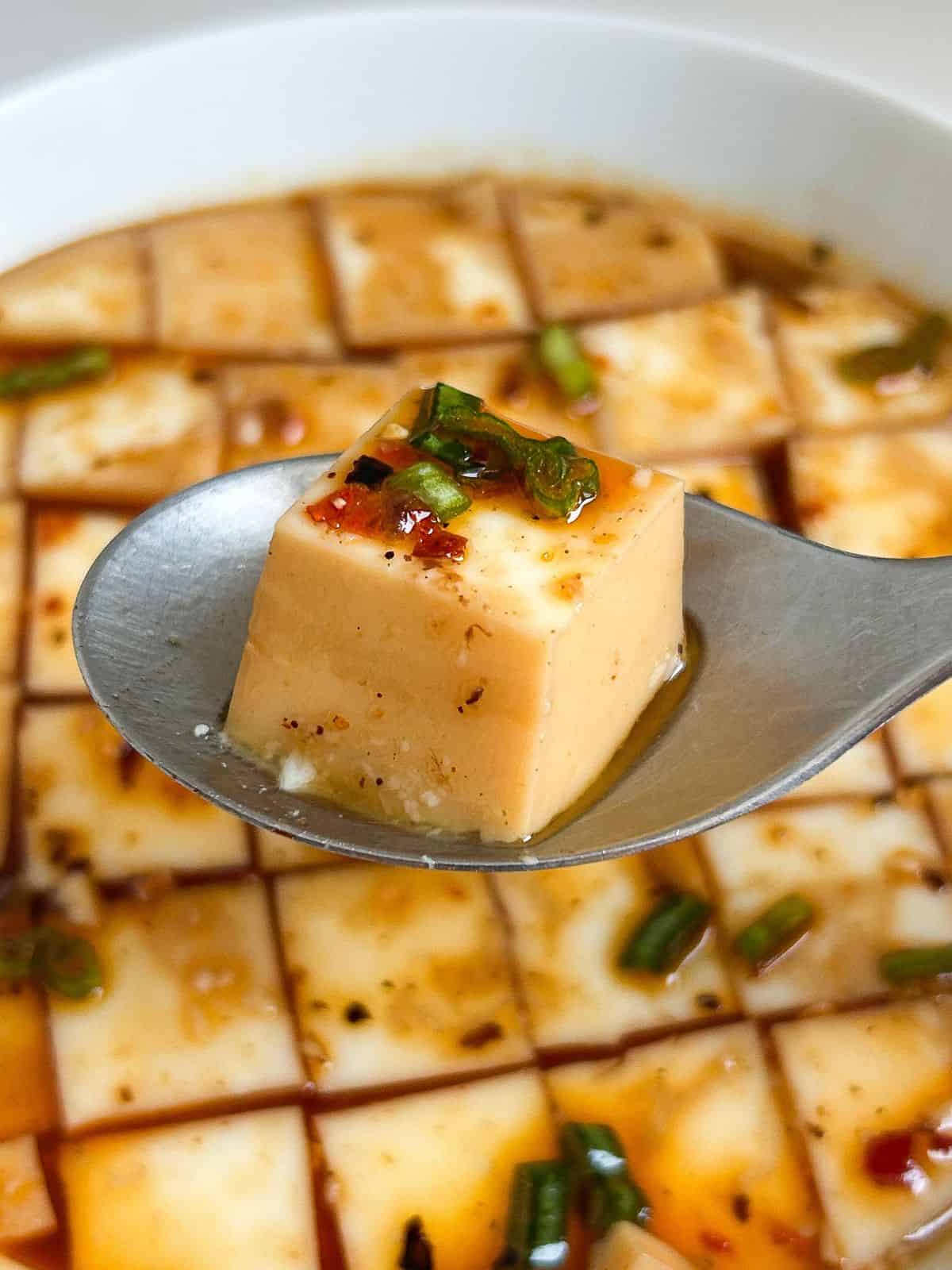 Chinese steamed egg whites cut into cubes with one cube on a spoon.