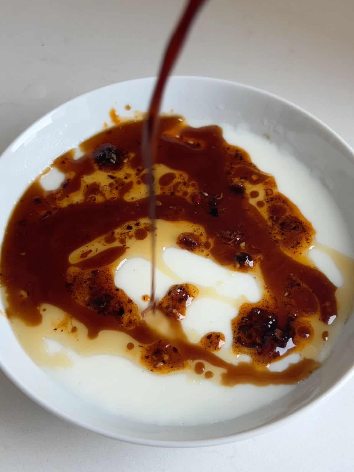 Pouring a sauce on top of the steamed egg whites in a bowl.