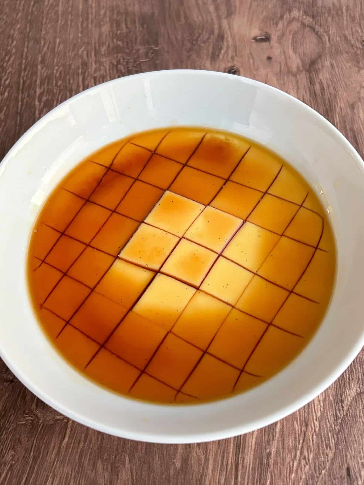 Microwave flan in a bowl and sliced into cubes with homemade caramel on top. 