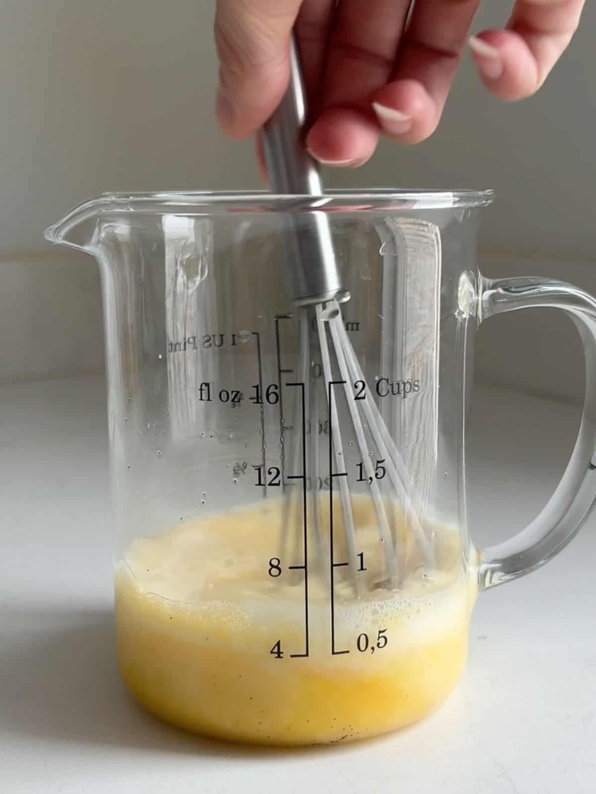 Flan ingredients being whisked in a measuring cup. 