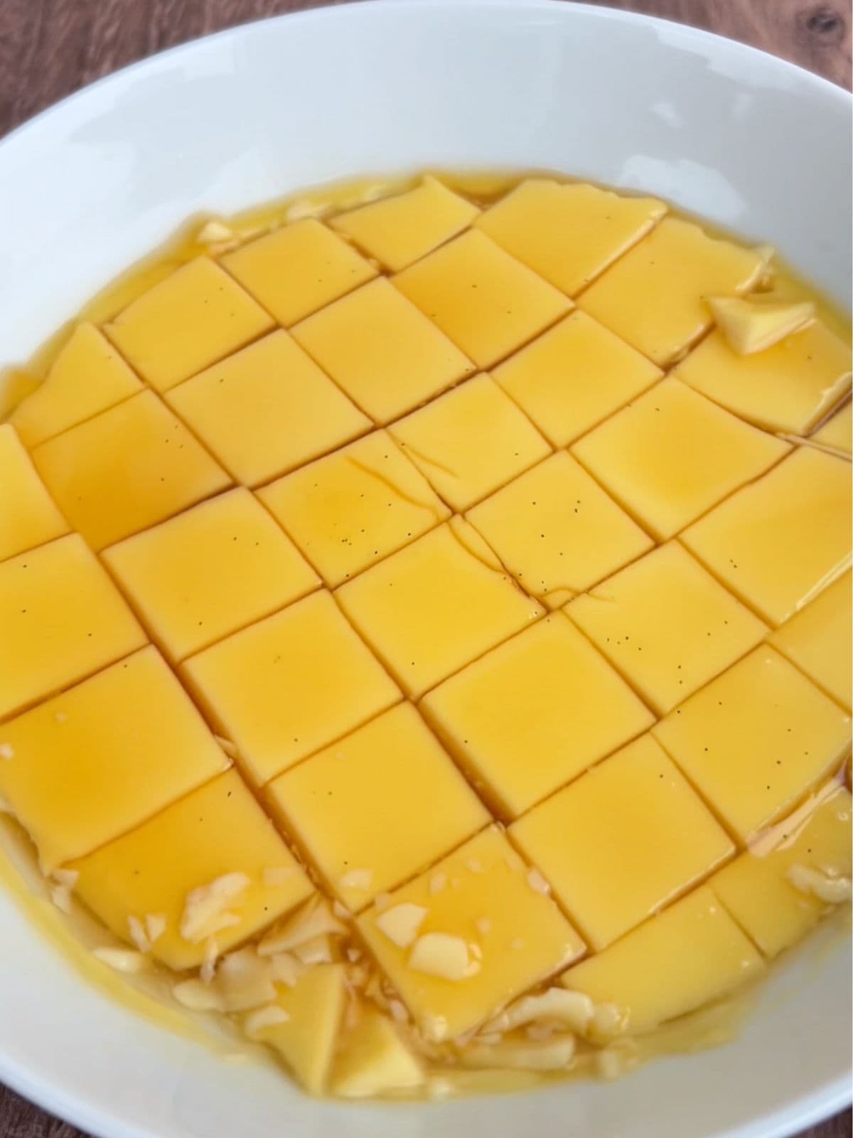 Flan cut into cubes with caramel mixture on top in a bowl. 