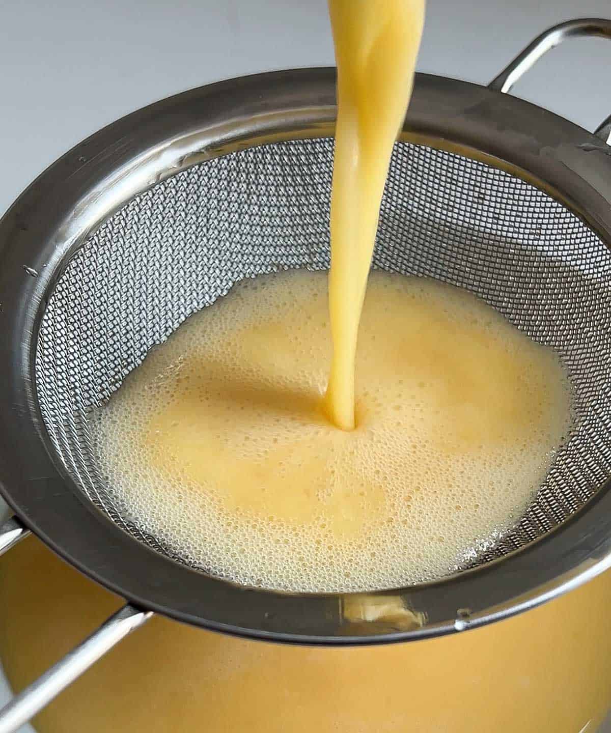 egg mixture poured through a fine mesh sieve into a microwave safe bowl.