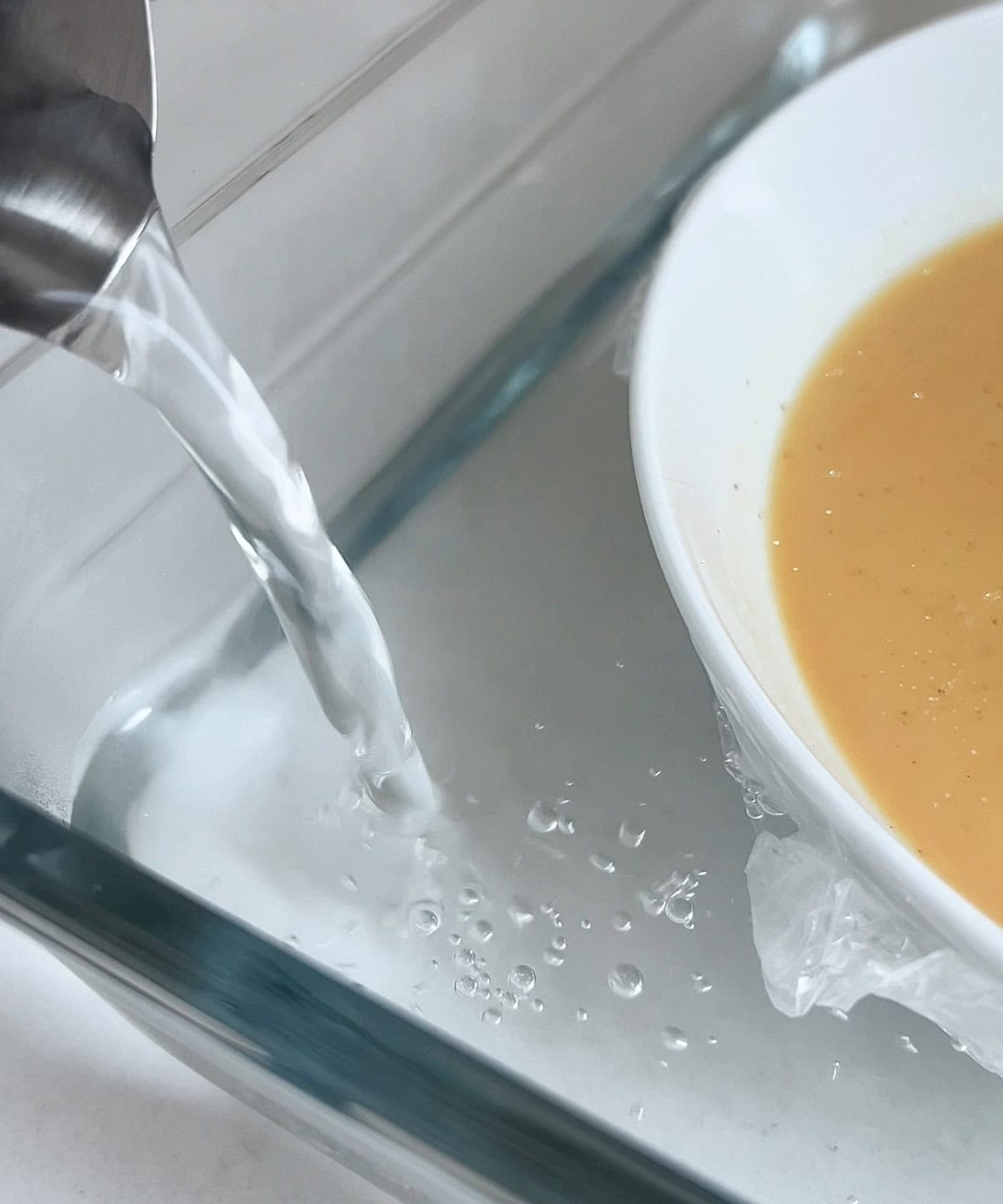 water being poured into a microwave safe dish to make the water bath for the steamed flan.