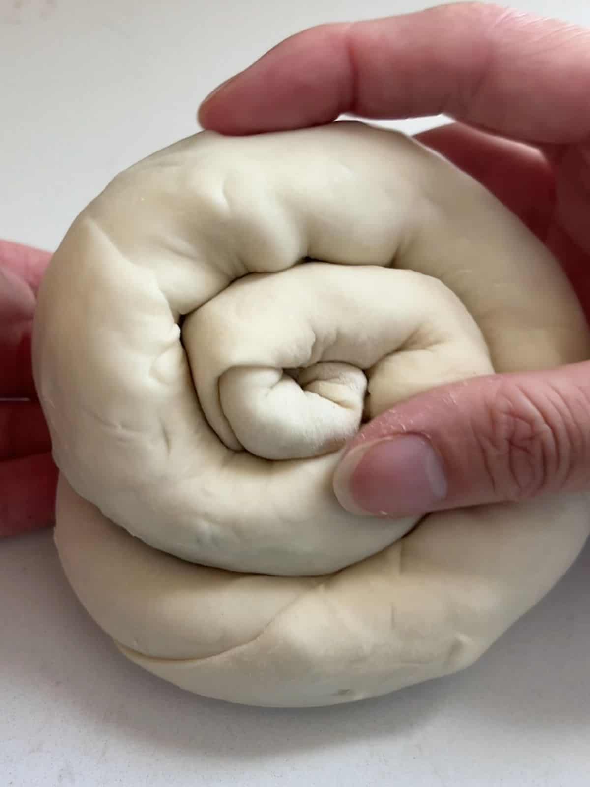 Rolling up the layered scallion pancake dough into a spiral shape.