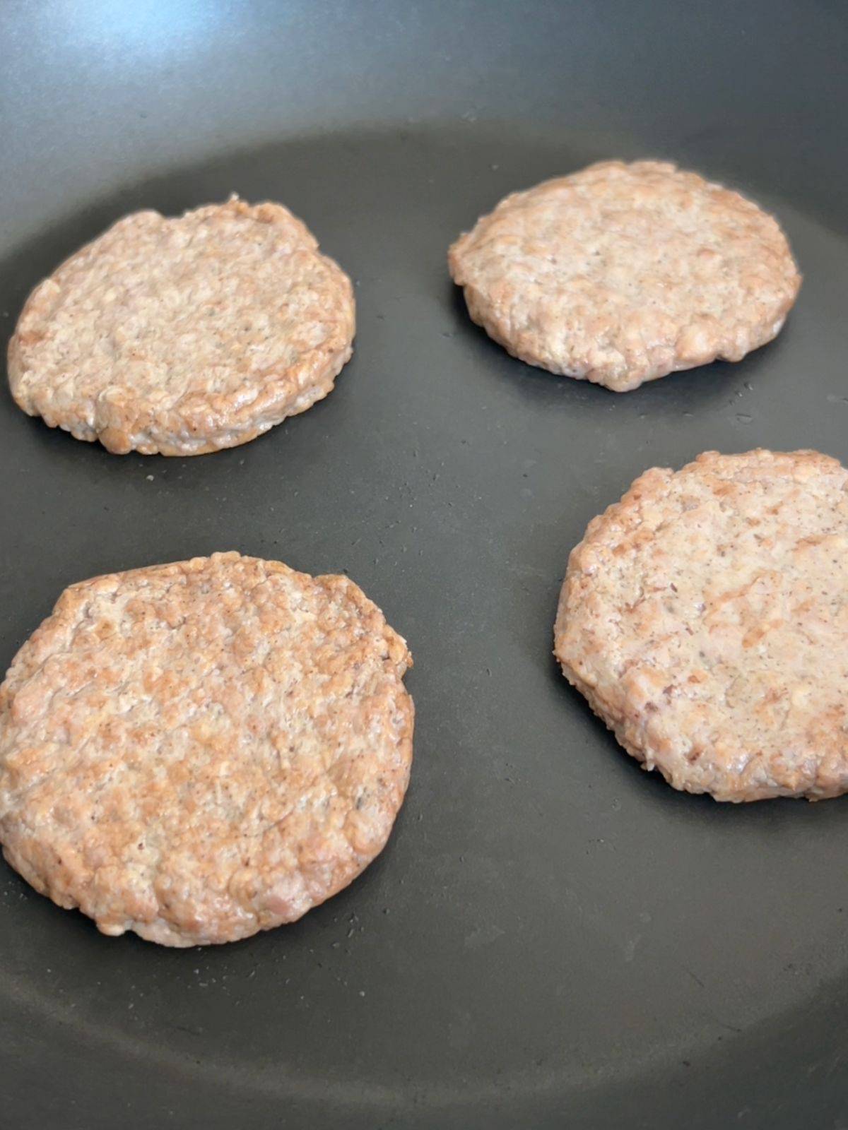 Turkey sausages being cooked in a skillet.