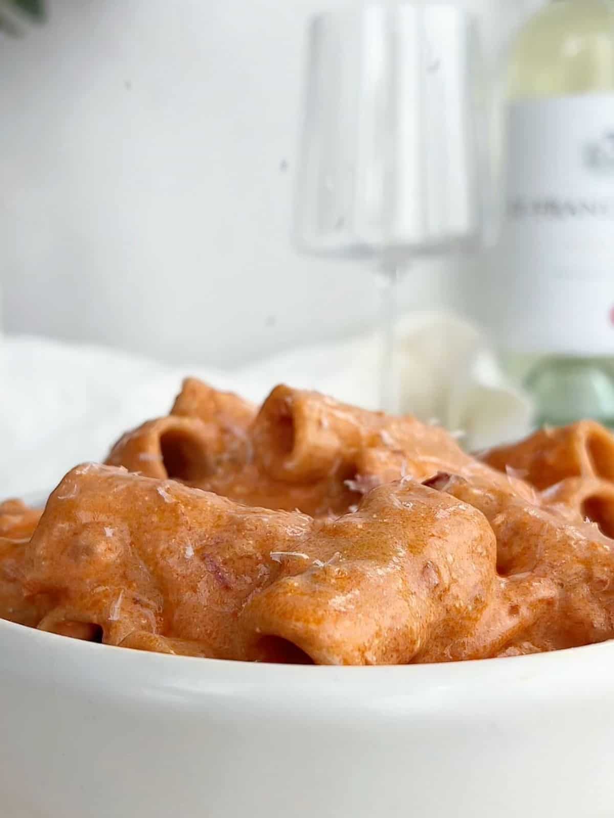 Side view of creamy spicy vodka pasta in a white bowl.