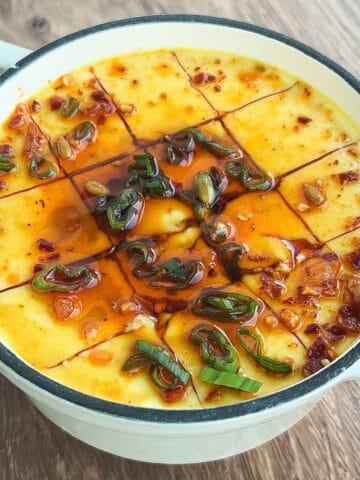 steamed eggs in pot with scallions, sesame oil, soy sauce, and chili oil.