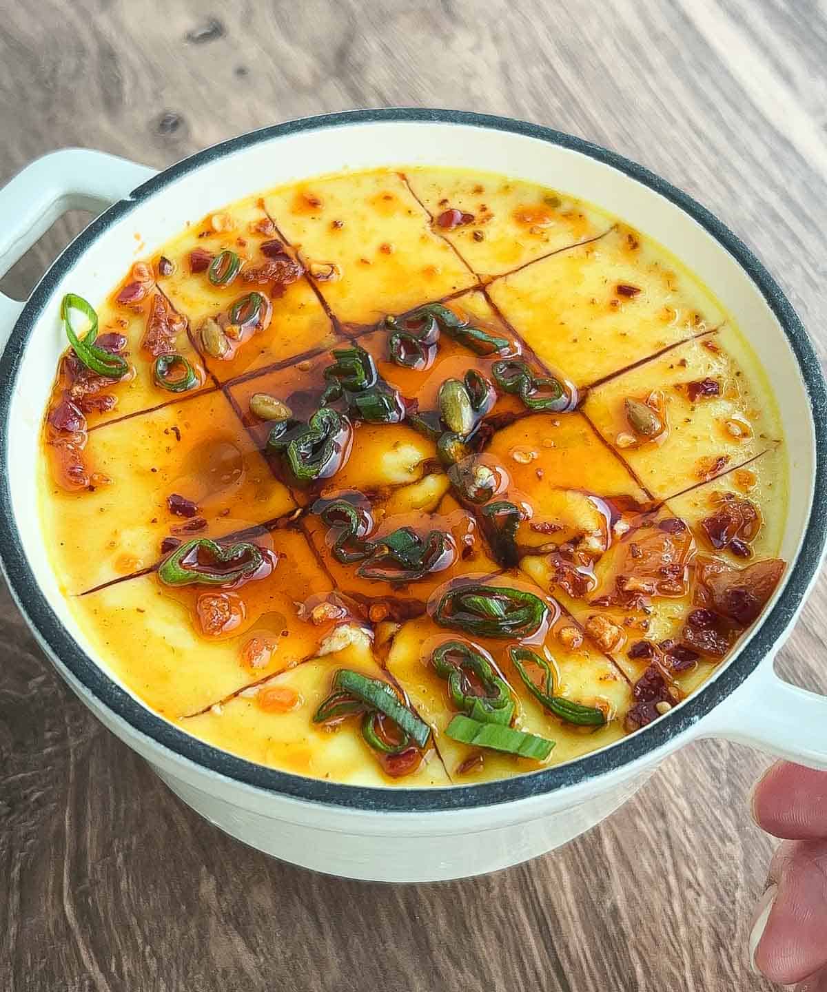 steamed eggs in pot with scallions, sesame oil, soy sauce, and chili oil.