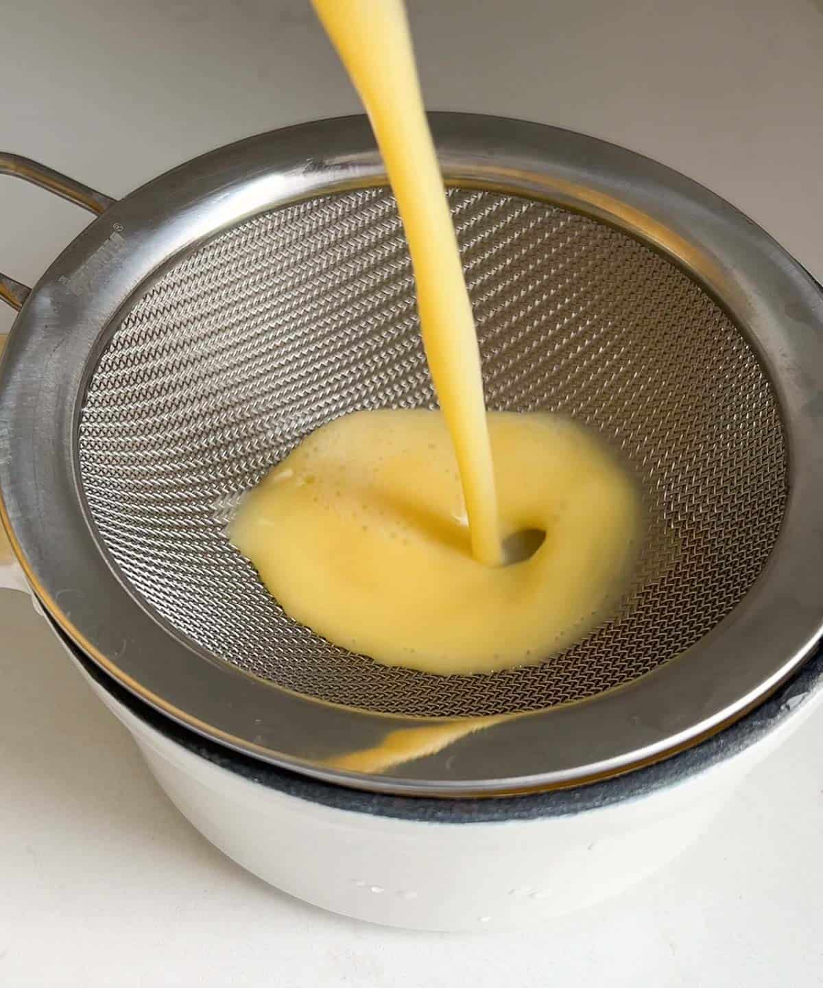 egg mixture poured through a fine mesh sieve into a heat-safe dish.