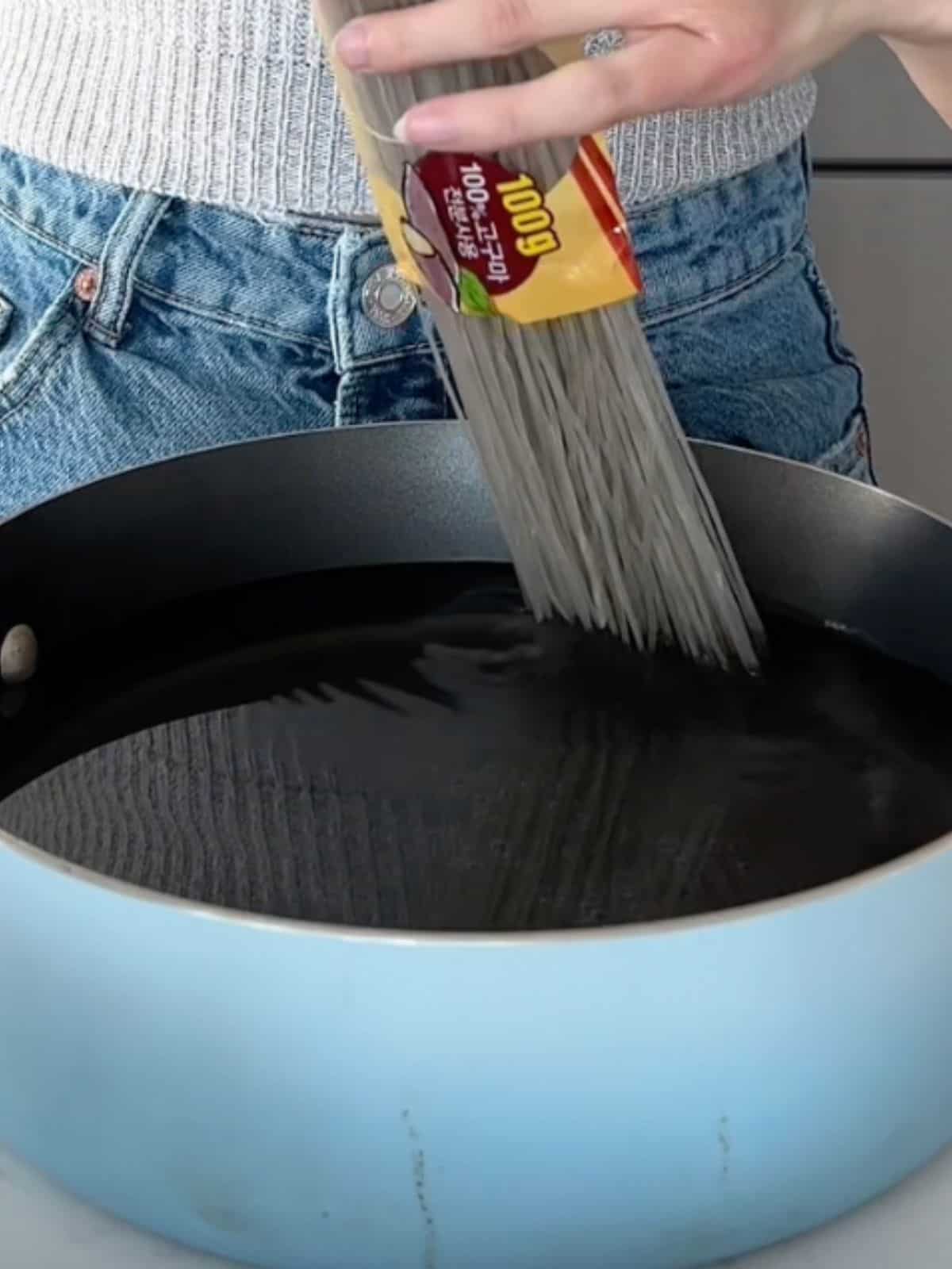 Sweet potato noodles being placed into warm water. 