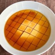 Microwave flan in a bowl sliced into cubes with a caramel layer on top.