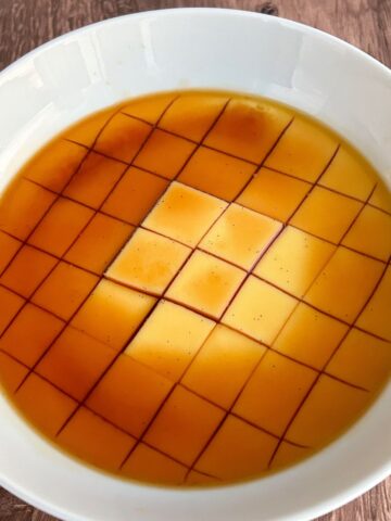 Microwave flan in a bowl sliced into cubes with a caramel layer on top.