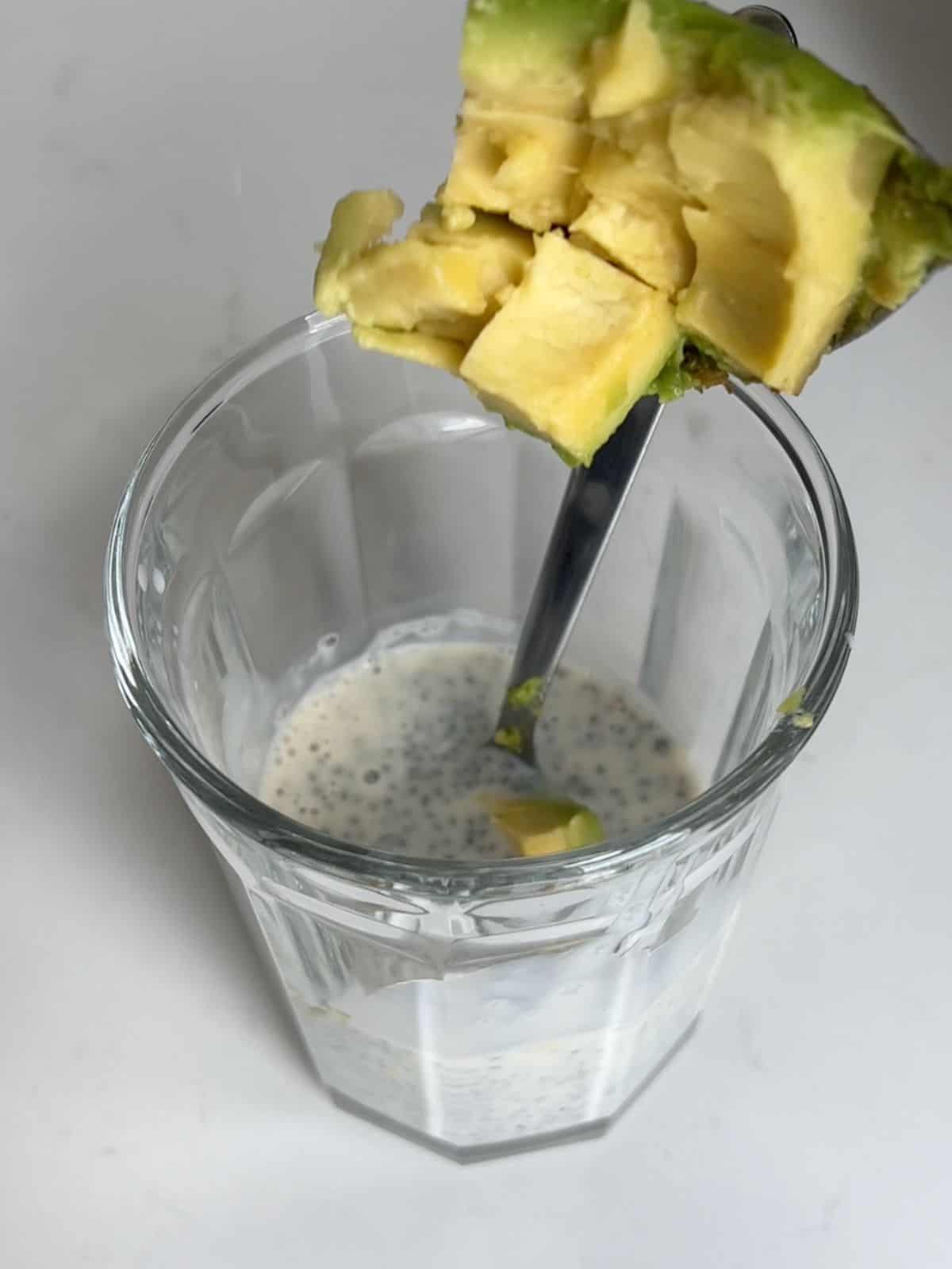 Diced avocado being added into the chia seeds and milk.