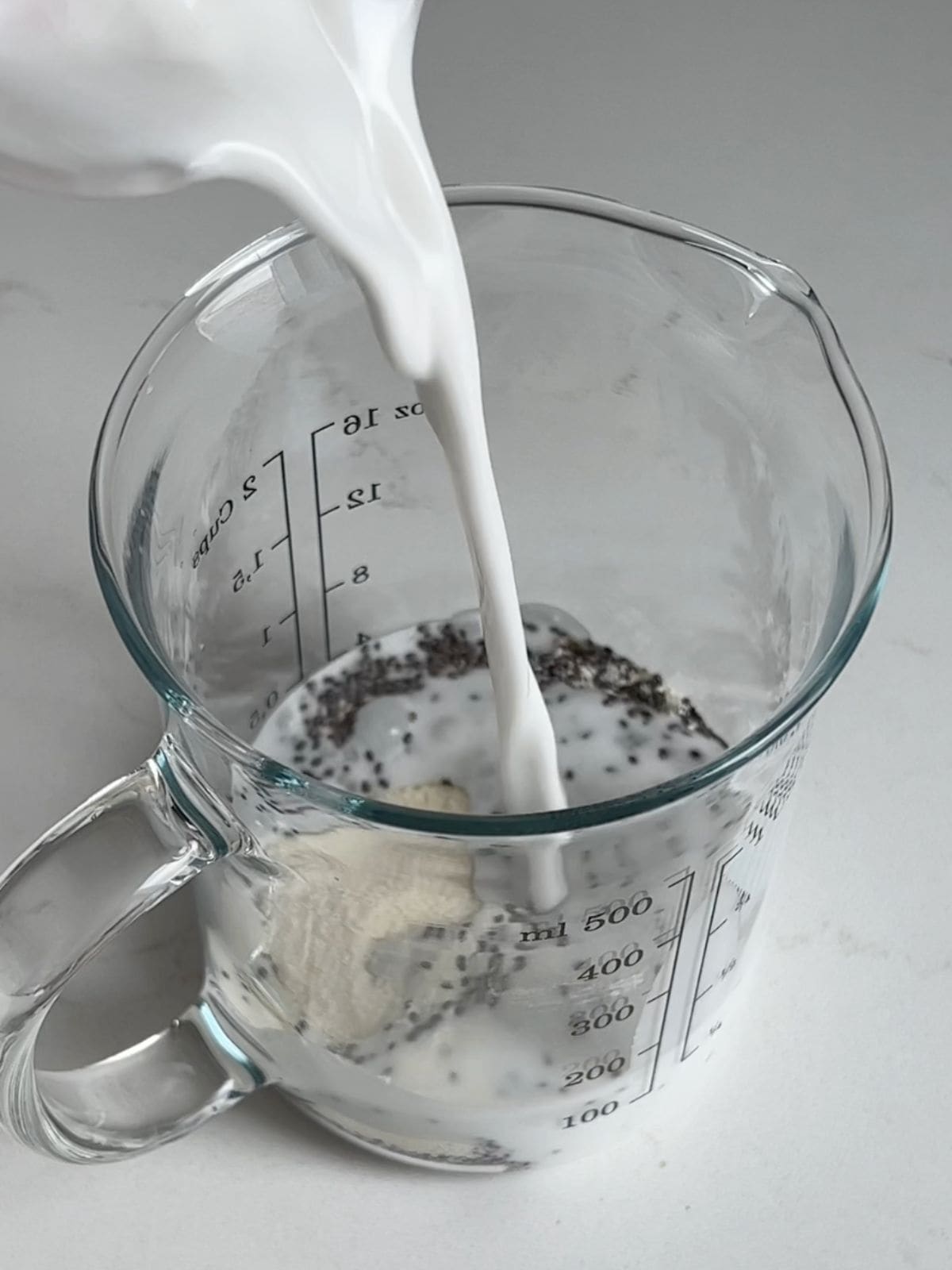 Combing milk, chia seeds and protein powder in a liquid measuring cup.