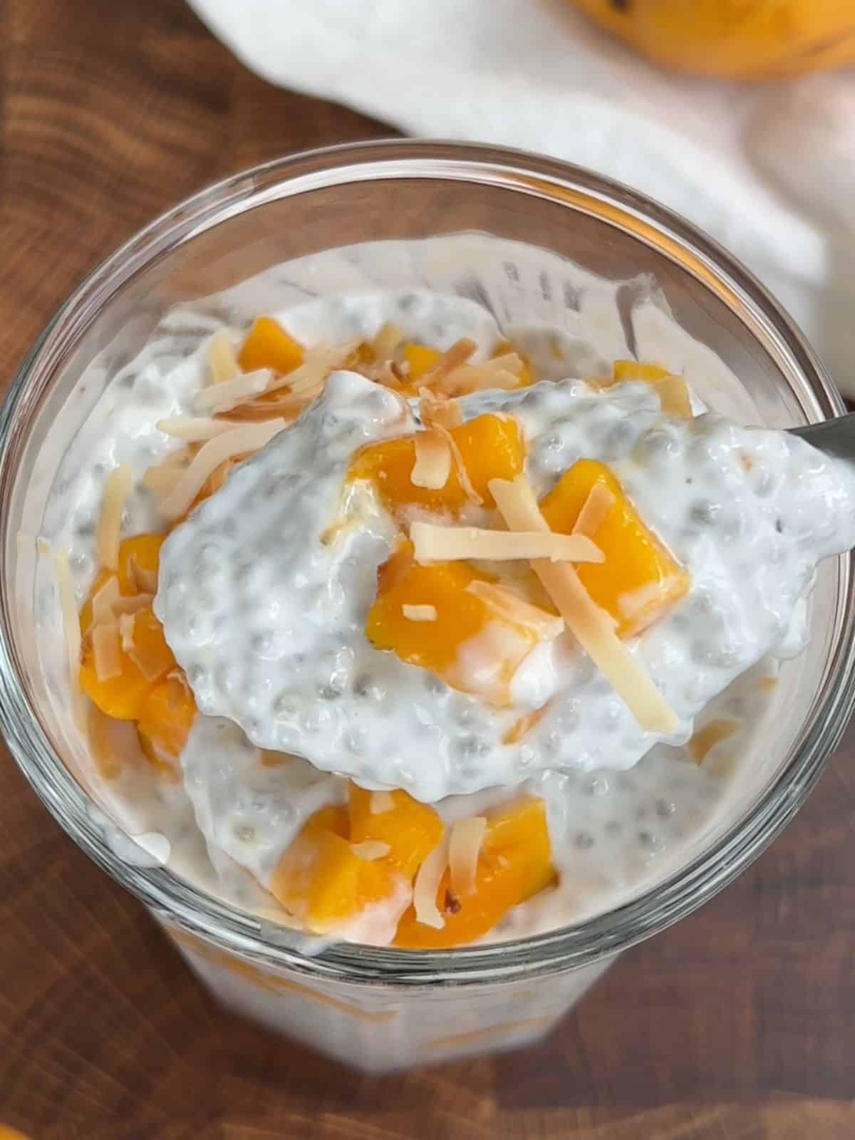 Spoon taking a portion of chia mango pudding from the cup.