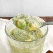 Avocado chia pudding in a glass with a spoonful of it hovering over the top.