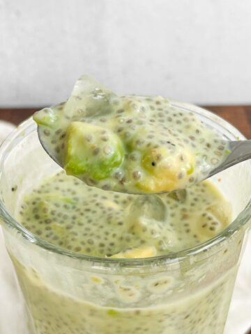 Avocado chia pudding in a glass with a spoonful of it hovering over the top.