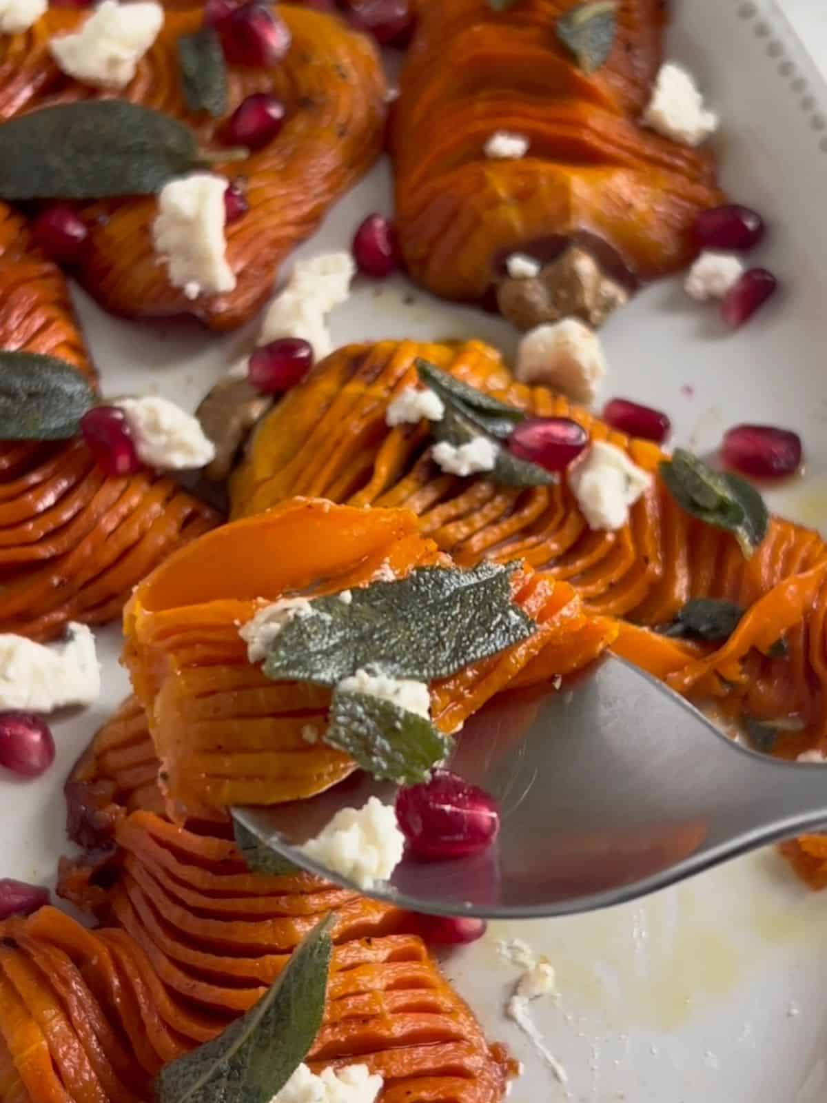 Spoon scooping up a bite of squash with sage, cheese and pomegranate.