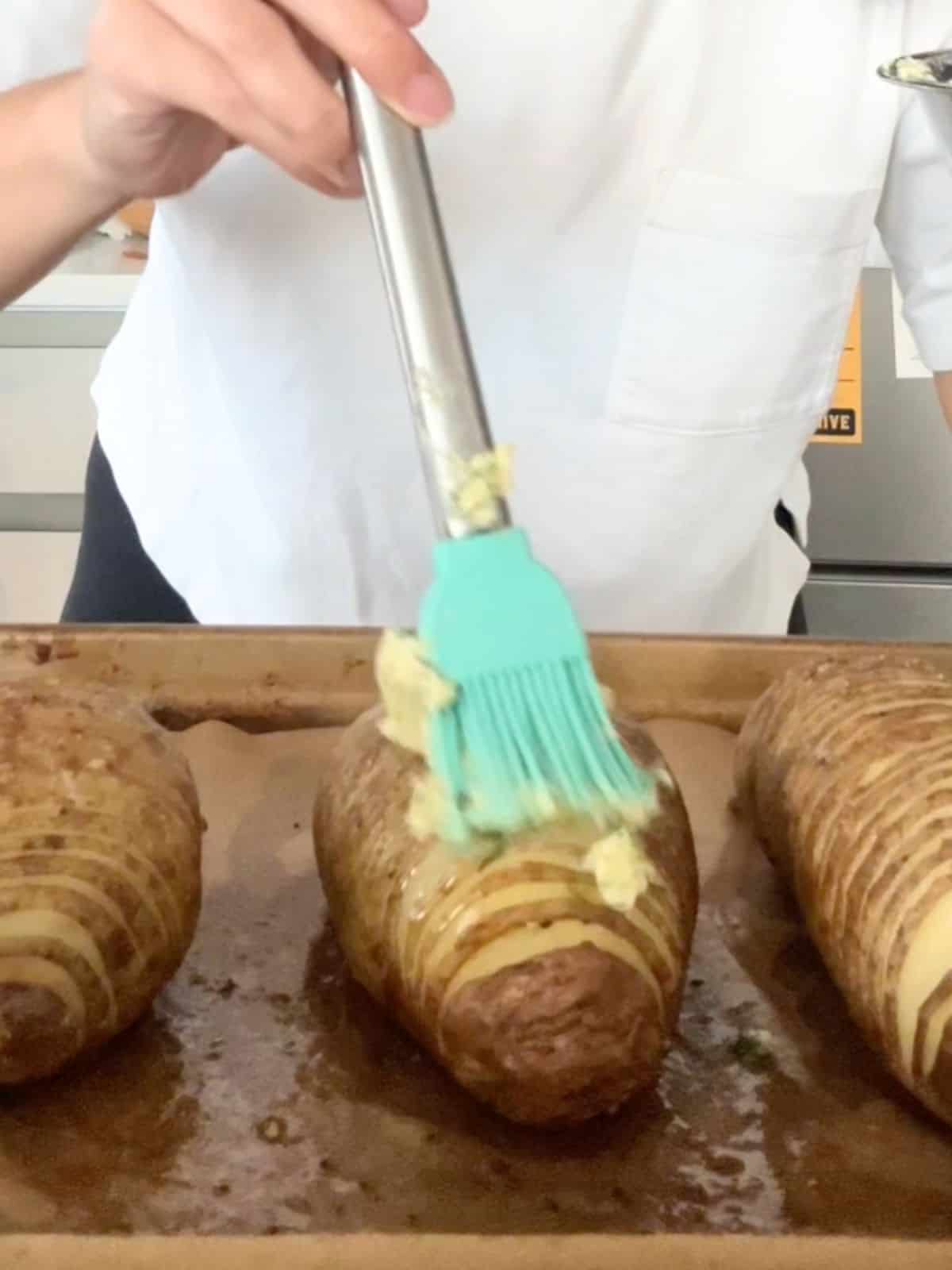 Brushing fish sauce butter onto the baked potatoes before baking them again.