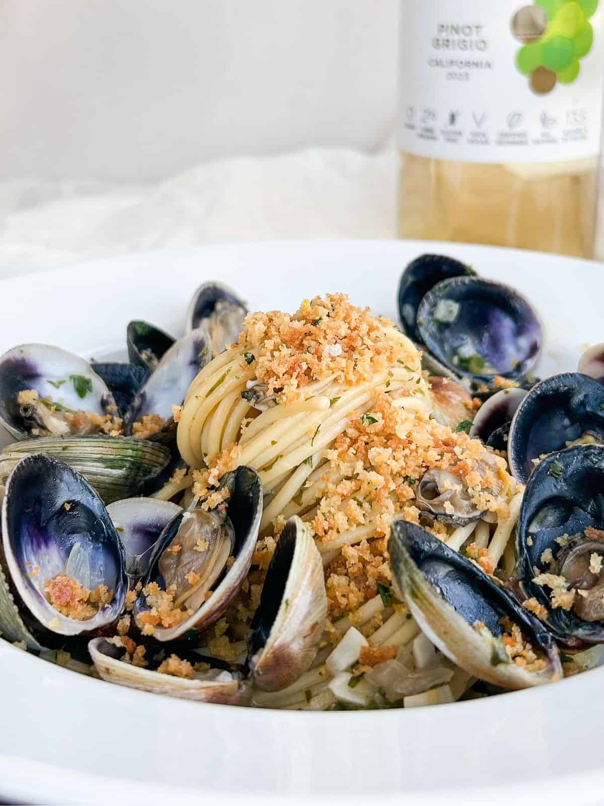 Side view of a bed of spaghetti surrounded by clams and topped with breadcrumbs