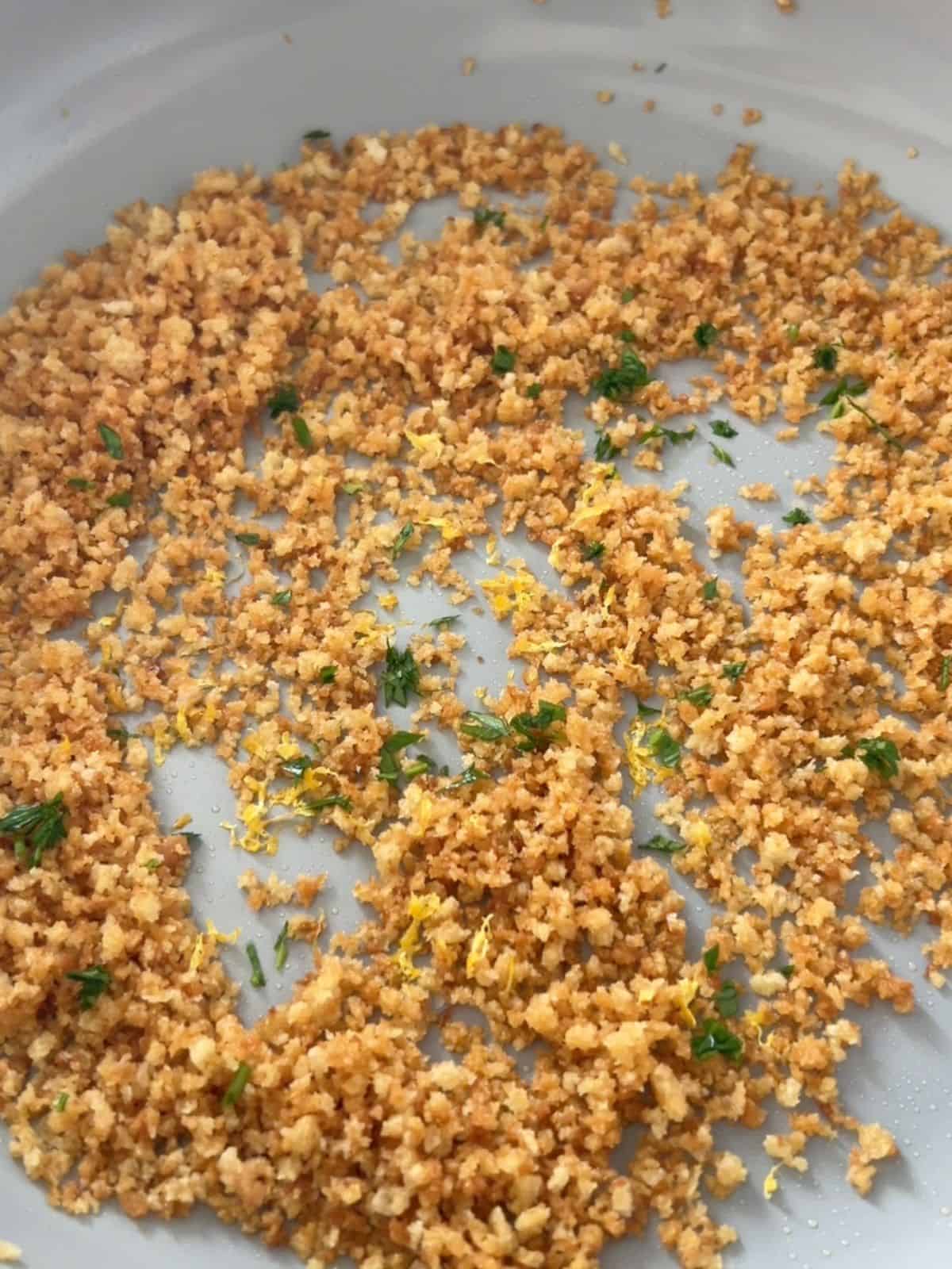 Breadcrumbs with lemon zest and parsley in a pan.