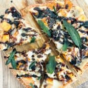 Overhead shot of butternut squash flatbread cut into slices on a wooden background.