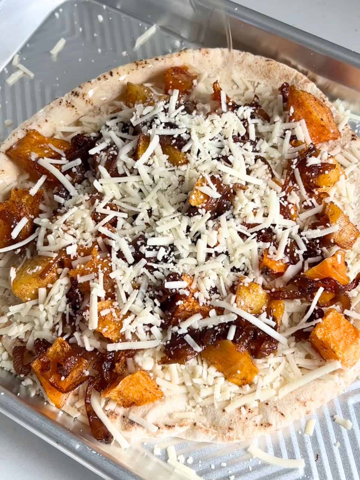 Assembling the butternut squash flatbread on a sheet pan before baking it.