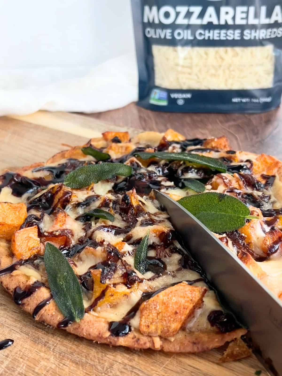 Using a knife to slice the butternut squash flatbread after baking.