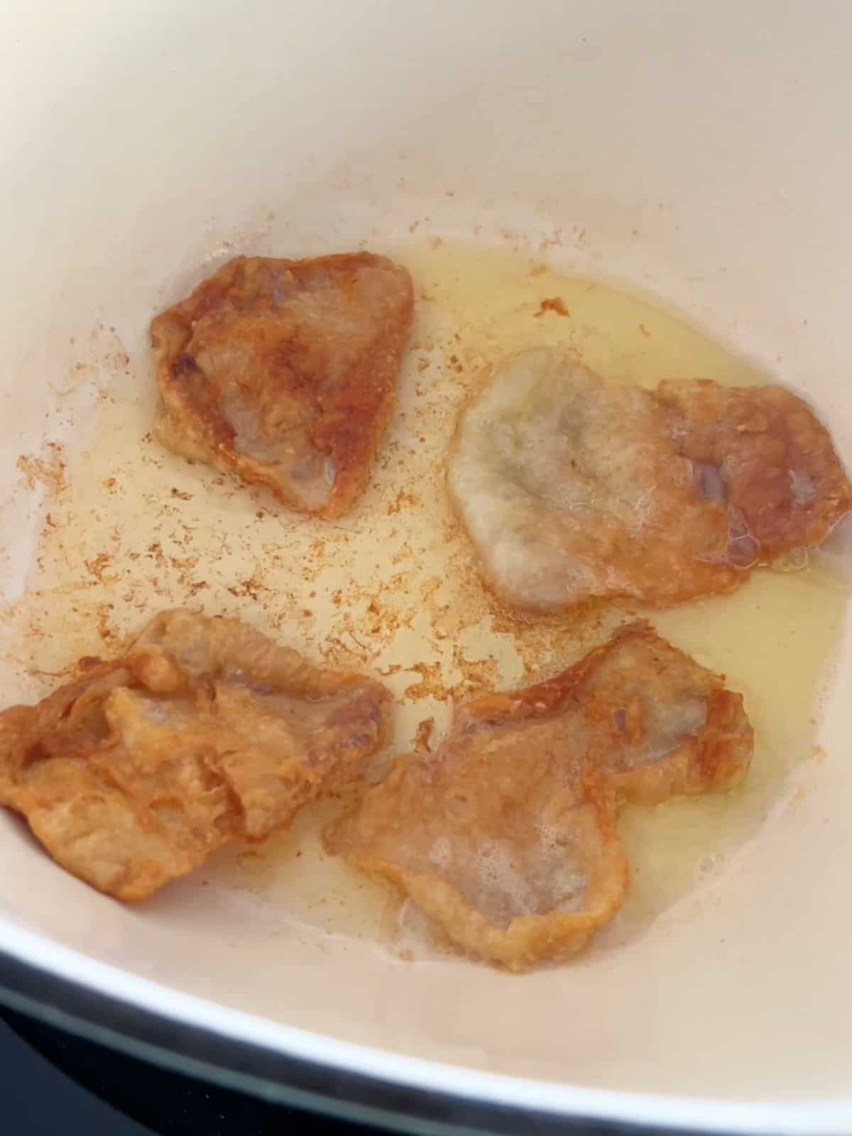 Crispy fried chicken skins in a large pot.