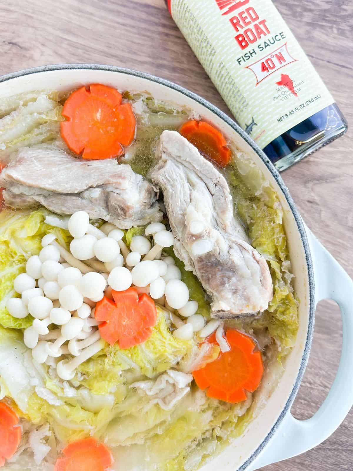 Mielle feuille nabe in a large Dutch oven next to a bottle of fish sauce.