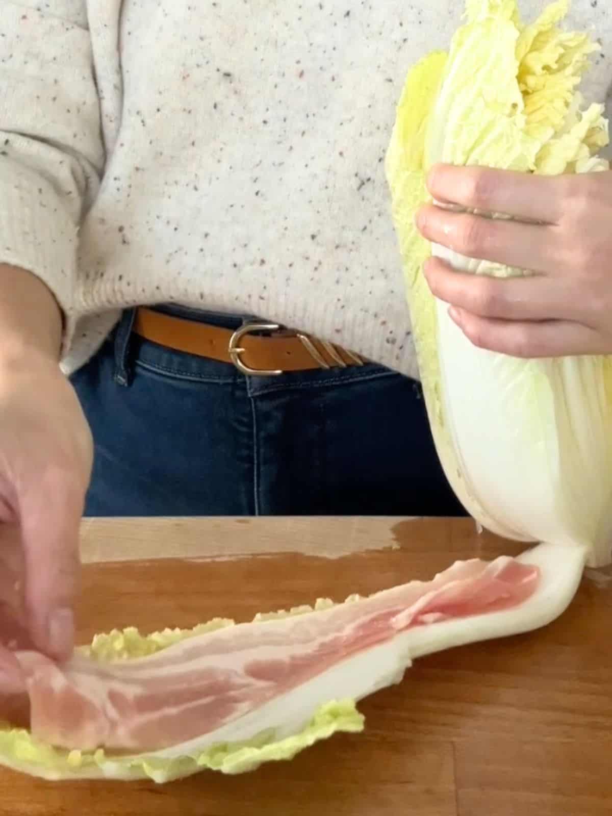 Layering pork belly in between the layers of napa cabbage.