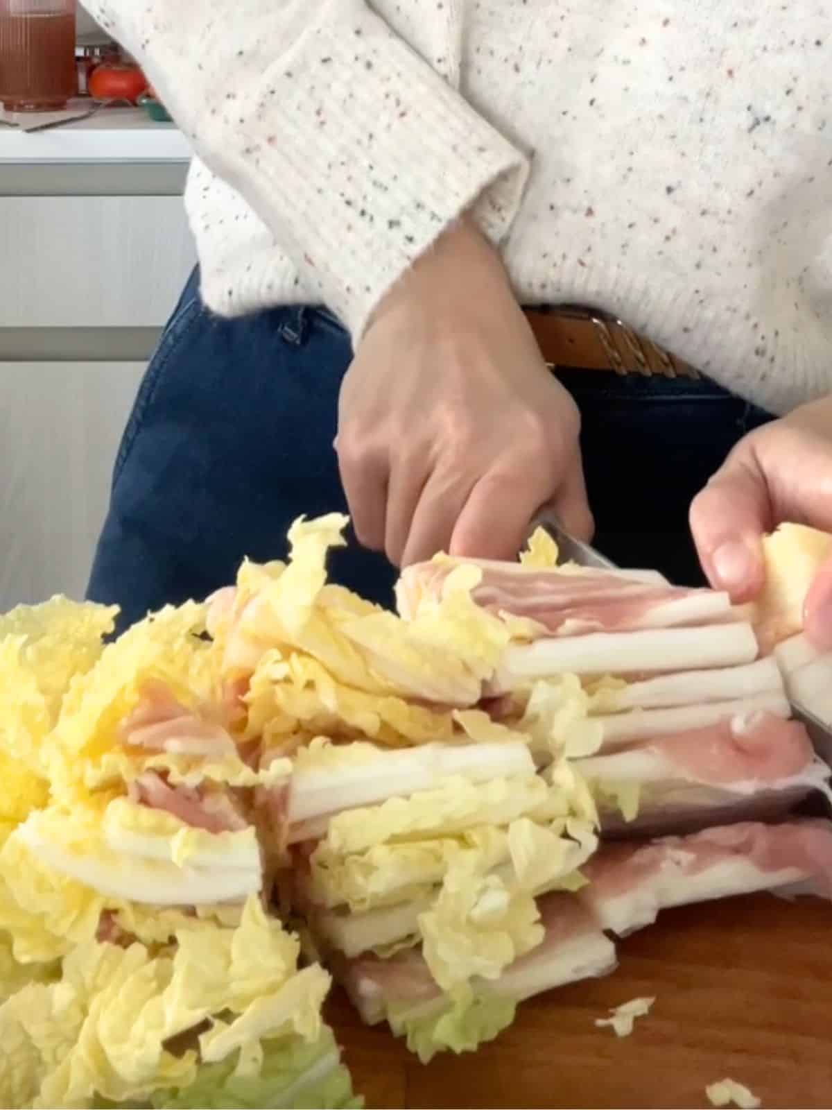 Slicing the napa cabbage with layers of pork belly into thick pieces.