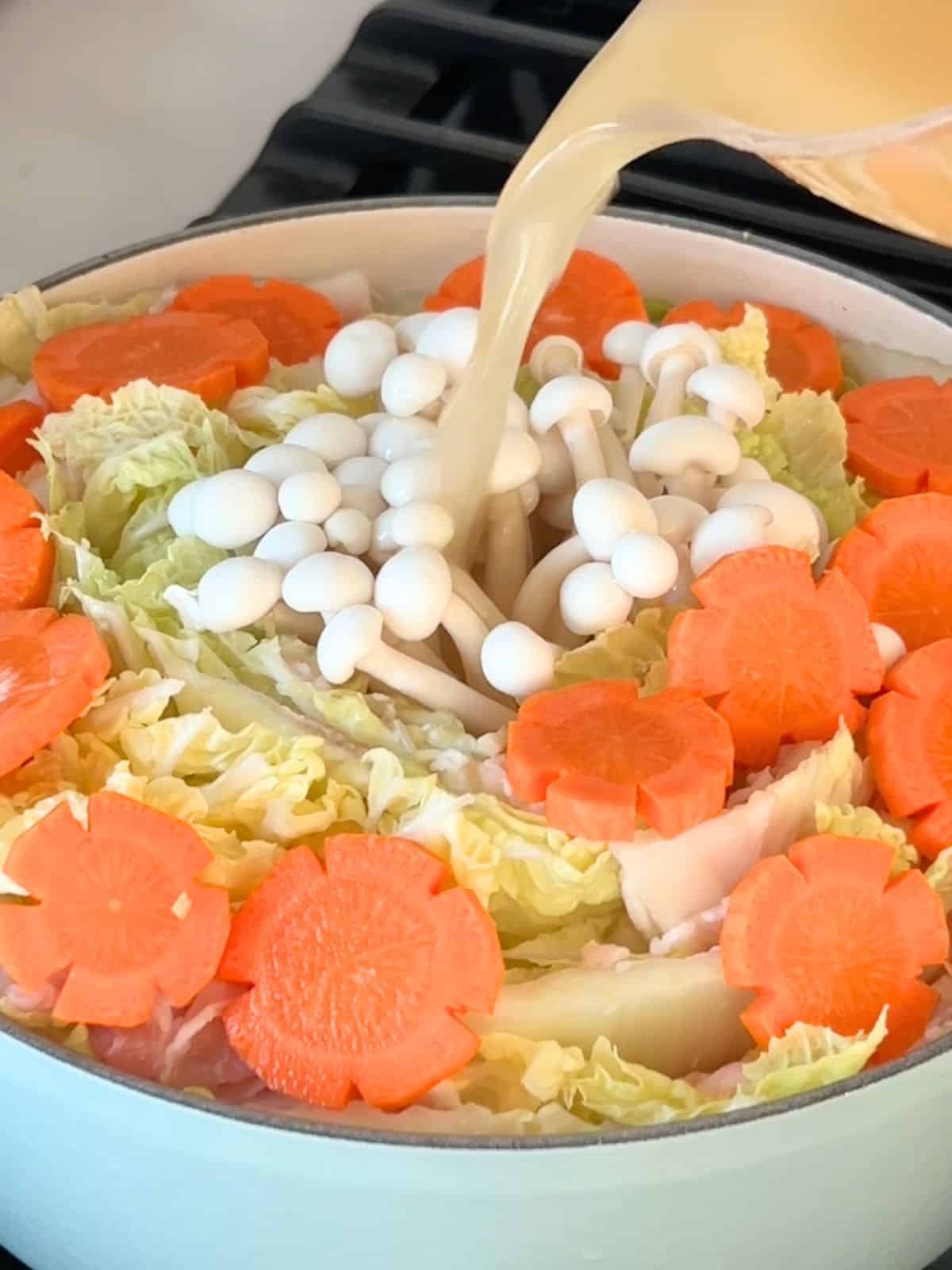 Pouring the prepared broth into the mille feuille nabe before allowing it to steam.