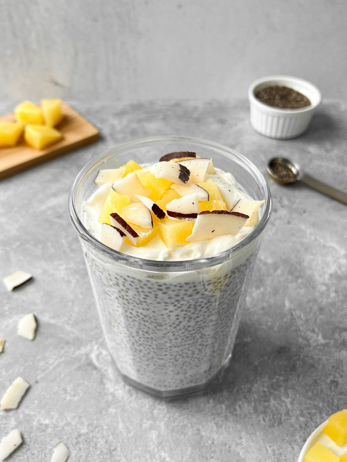 Pina colada chia pudding served in a glass cup topped off with pineapples and coconut flakes.