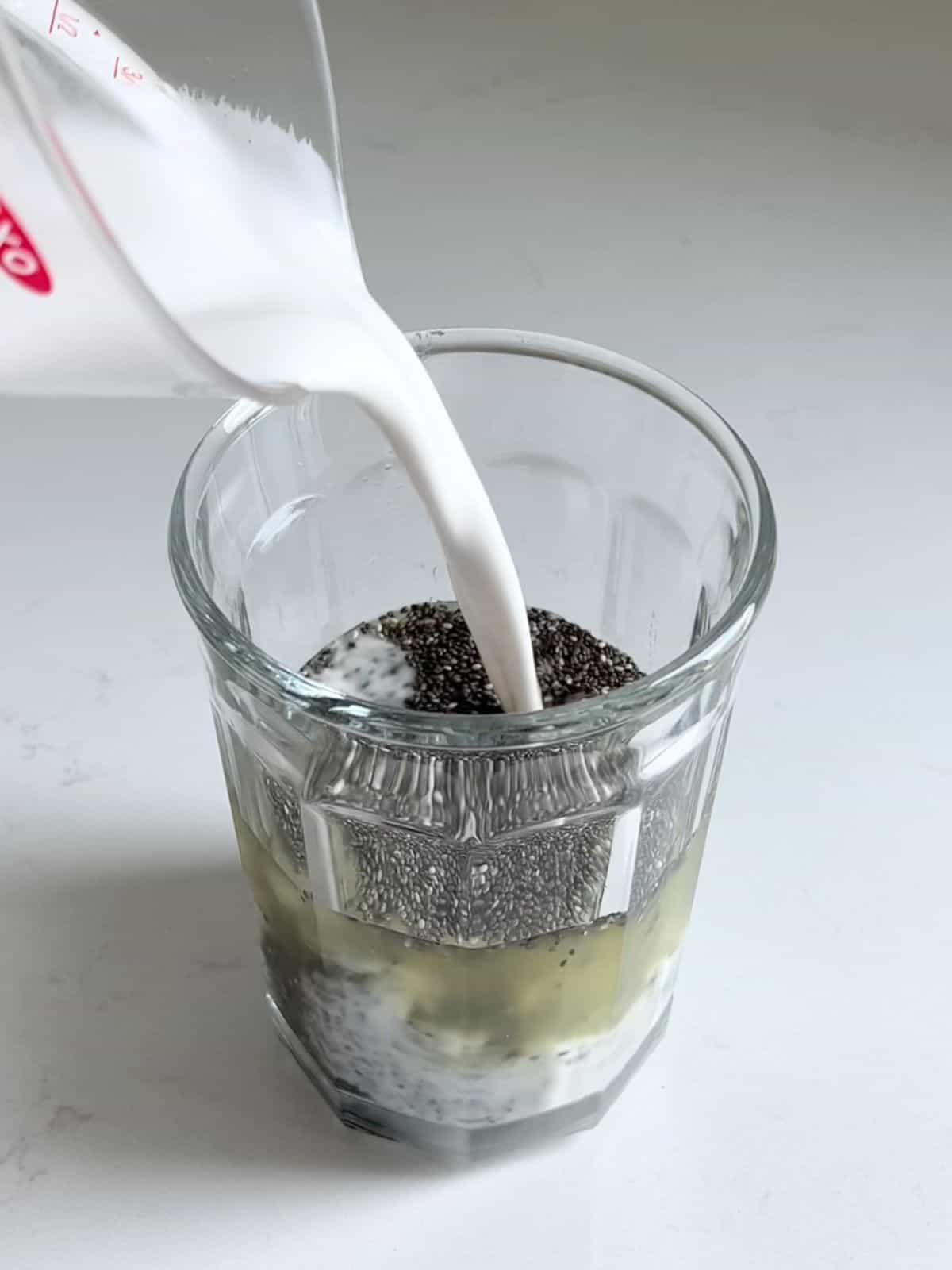 Combining chia seeds, pineapple juice and coconut milk in a glass.