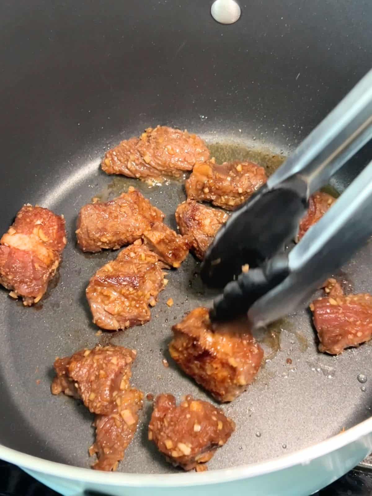 Searing the cubed beef in a large pot.